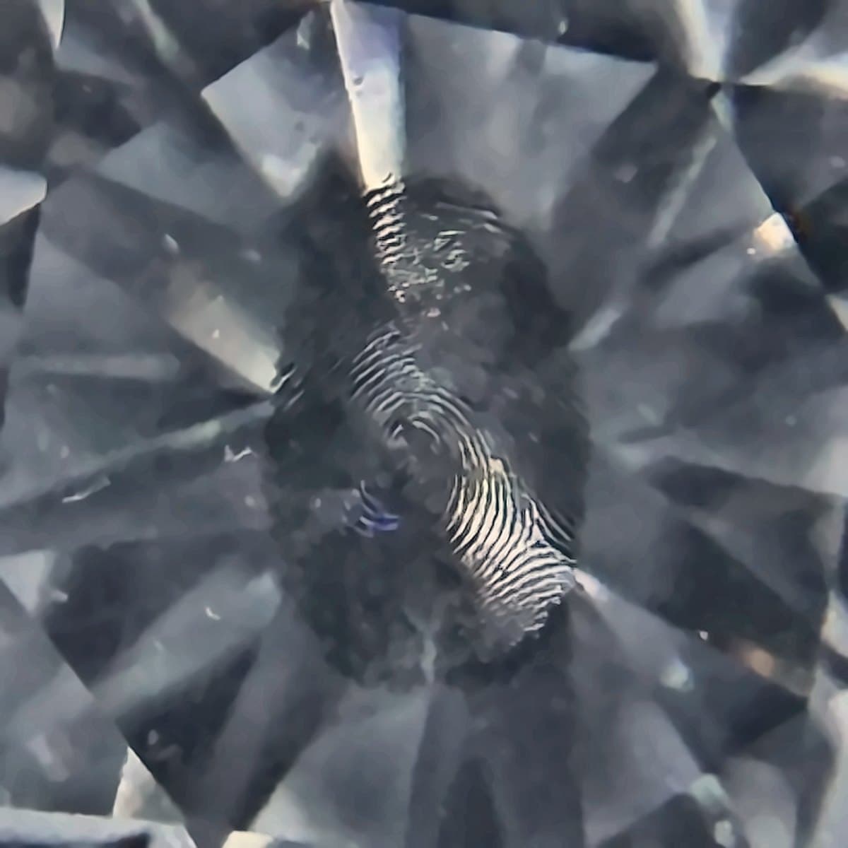 Gravierter Diamant unter der Lupe — Fingerabdruck